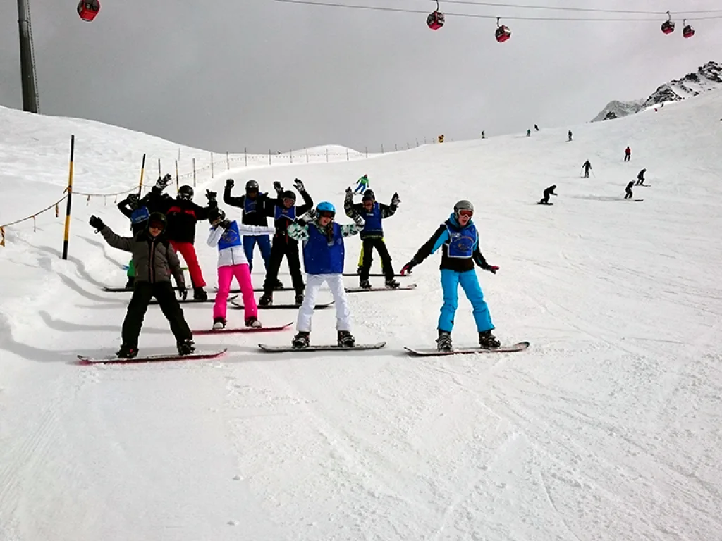 Gruppe mit Snowboards posiert am Hang.